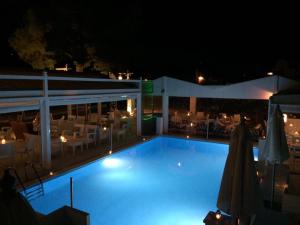 a large swimming pool at night with tables and chairs at Nidri Bay Studios in Nydri