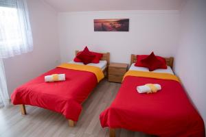duas camas num quarto com lençóis vermelhos e amarelos em Relax Guest House Blagaj em Blagaj