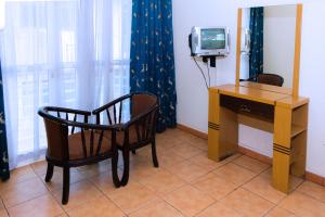 a room with a desk and a chair and a television at Aponye Hotel Kampala in Kampala