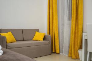 a couch with yellow curtains in a living room at LA CIVITA B&B in Gravina in Puglia