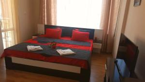 a bedroom with a bed with red pillows and a television at Family Hotel Solar Central in Sunny Beach
