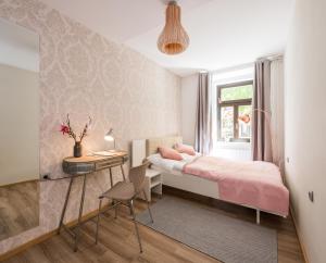 ein kleines Schlafzimmer mit einem rosa Bett und einem Schreibtisch in der Unterkunft Royal Vega Apartment in Ljubljana