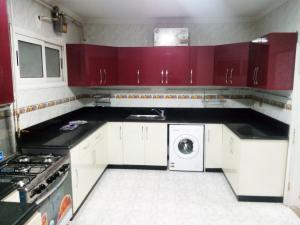 une cuisine avec des placards rouges et un lave-linge/sèche-linge dans l'établissement Apartment at Milsa Nasr City, Building No. 22, au Caire