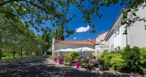 a courtyard of a building with tables and umbrellas at LOGIS Hôtel Le Moulin Des Gardelles in Riom