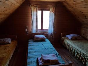 Cette chambre mansardée comprend 2 lits et une fenêtre. dans l'établissement Pirmie Zaļmeži, à Jūrkalne
