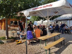 un grupo de personas sentadas en mesas bajo un paraguas en Hotel Restaurant Klostermühle, en Reutlingen