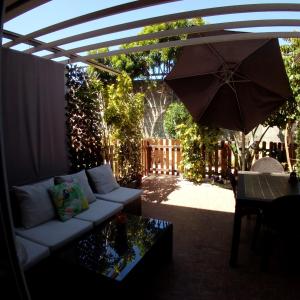 a patio with a white couch and an umbrella at Casa Green Oasis in Maspalomas