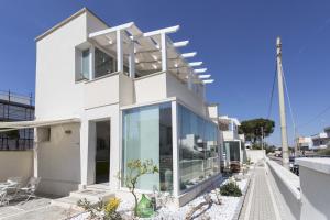 uma casa branca com grandes janelas de vidro em Viva Vacanze em Porto Cesareo