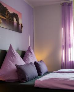 1 dormitorio con 1 cama con almohadas moradas y blancas en Zimmervermietung Hebenstreit en Bernburg