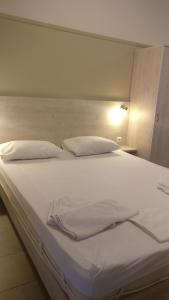 a large white bed with white sheets and pillows at Kleri Beloni Rooms in Chania Town