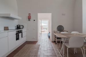 タヴィラにあるConvento das Bernardas Taviraの白いキャビネット、テーブルと椅子付きのキッチンが備わります。
