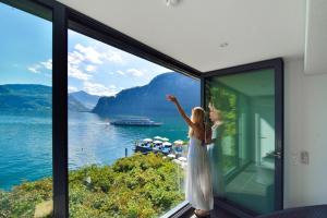 a woman standing in front of a window looking out at the water at Seehotel Pilatus in Hergiswil