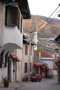 una calle con edificios y un coche rojo en una ciudad en Welcome, en Sarajevo