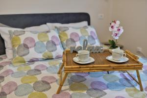 - un lit avec un plateau avec des tasses et des soucoupes dans l'établissement Apartman Alex Zlatibor, à Zlatibor