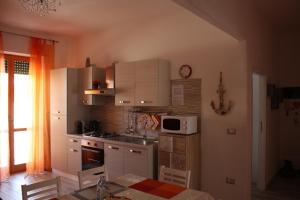a kitchen with white cabinets and a table and a microwave at House of colours - Relax, arte e confort per coppie, famiglie e gruppi in Alghero