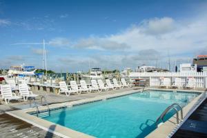 a swimming pool with lounge chairs and a boat at Anchorage Inn & Marina in Ocracoke