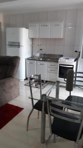 a kitchen with white appliances and a table and chairs at Apartamento Aconchegante em Foz in Foz do Iguaçu