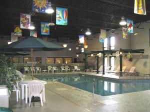 a swimming pool with tables and chairs and an umbrella at Colonial Inn in Brandon
