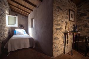 a bedroom with a bed in a stone wall at Casale Amati Country House in Ortonovo