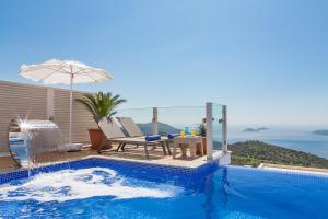 a swimming pool with a table and an umbrella at Villa La Mer Azur in Kalkan