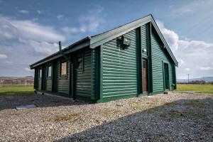 a small green building on a gravel field at Altnaharra Hotel in Lairg