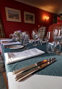 una mesa con vasos y cubiertos. en Altnaharra Hotel, en Lairg