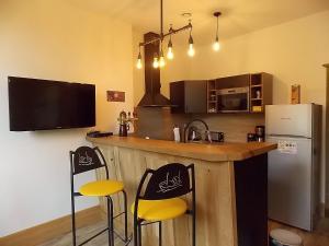 a kitchen with a bar with two chairs and a refrigerator at Les Gîtes De Morville in Malaumont