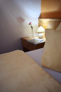 a bedroom with a bed and a vase with a flower on a night stand at Hotel zum Goldenen Wagen in Maulburg