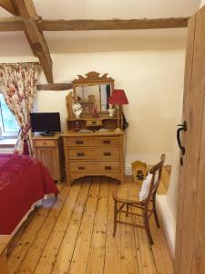 a bedroom with a bed and a dresser with a mirror at The Millers Cottage in Okehampton