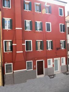 un edificio rojo con ventanas y una puerta en Appartamenti Vale Mare en Chioggia