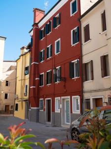 un edificio rojo con un coche aparcado delante de él en Appartamenti Vale Mare, en Chioggia