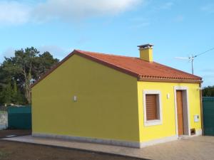 um edifício amarelo e verde com um telhado vermelho em O CORPIÑO DE CHORENTE em Muxia