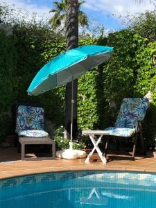 duas cadeiras e um guarda-sol junto a uma piscina em Ideal loft Malaga em Málaga
