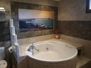 een badkuip in een badkamer met een schilderij aan de muur bij Hotel "Posada de Cantabria EL SOLAR" -Cenas típicas y Gintonic- Bar -Terraza panorámica in Galizano +166 foto's