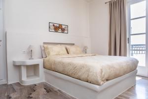 a white bedroom with a bed and a window at ALL SEASONS SUITE in Naxos Chora