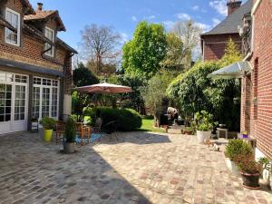 un patio con sombrilla, mesas y sillas en La Parenthese du Rond Royal, en Compiègne