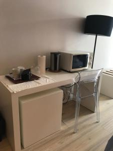 a desk with a microwave and a table with a chair at Quartos Do Seixe - Laranja in Odeceixe