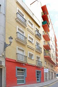 ein orangefarbenes und rotes Gebäude auf der Straßenseite in der Unterkunft Apartamentos Plaza in Alicante