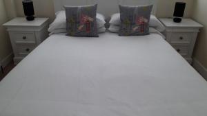 a white bed with two pillows on top of it at 8 Queenora Avenue in Portstewart