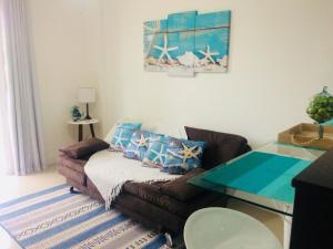ein Wohnzimmer mit einem Sofa und einem Glastisch in der Unterkunft Golden Lake in Arraial do Cabo
