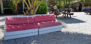 a red couch sitting on top of a sandy beach at Rangiroa Plage in Avatoru