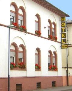 een wit gebouw met ramen en rode bloemen erop bij Hotel Monte Cristo in Offenbach