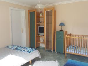 ein Schlafzimmer mit einem Kinderbett und einem TV in der Unterkunft Holiday home in Fonyod/Balaton 36989 in Fonyód