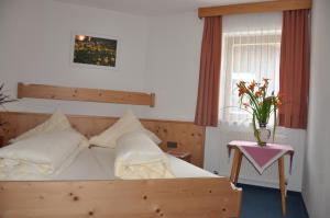 Un dormitorio con una cama de madera y un jarrón de flores en Hotel Kleon, en Vent