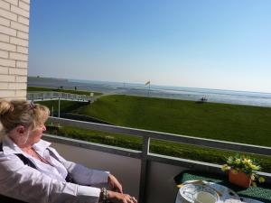 a woman sitting on a balcony looking at the beach at Haus Nordstrand Möwenweg 22 in Büsum