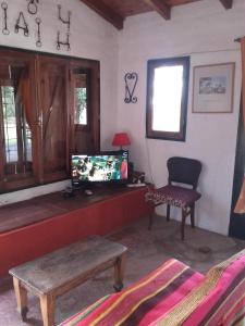 sala de estar con TV, mesa y silla en Casa de Campo Udea en Agua de Oro