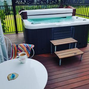 a hot tub on a deck with a table and a coffee cup at Tambo Tranquility in Mount Tamborine