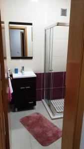 a bathroom with a sink and a shower with a mirror at Jessica Appartment in Praia