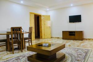 a living room with a table and a tv on a wall at CasaHouse Apparts in Nouakchott