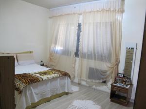 a bedroom with a bed and a window with curtains at Santa Rosa do Sul - SC in Sombrio